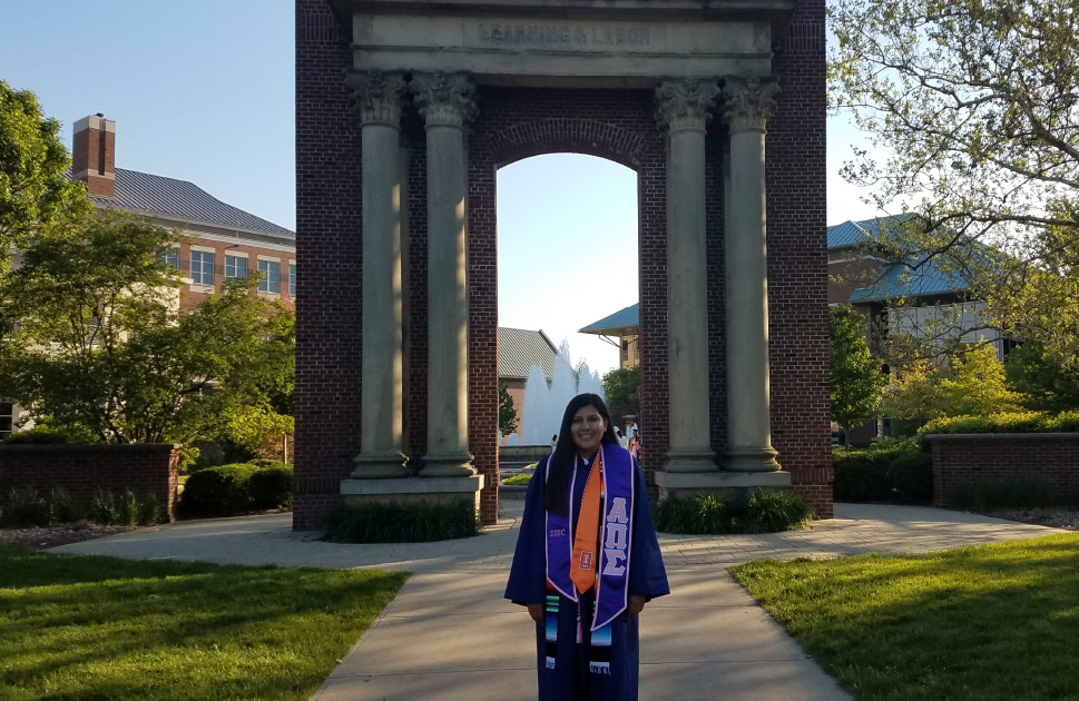 graduate standing in front of arch